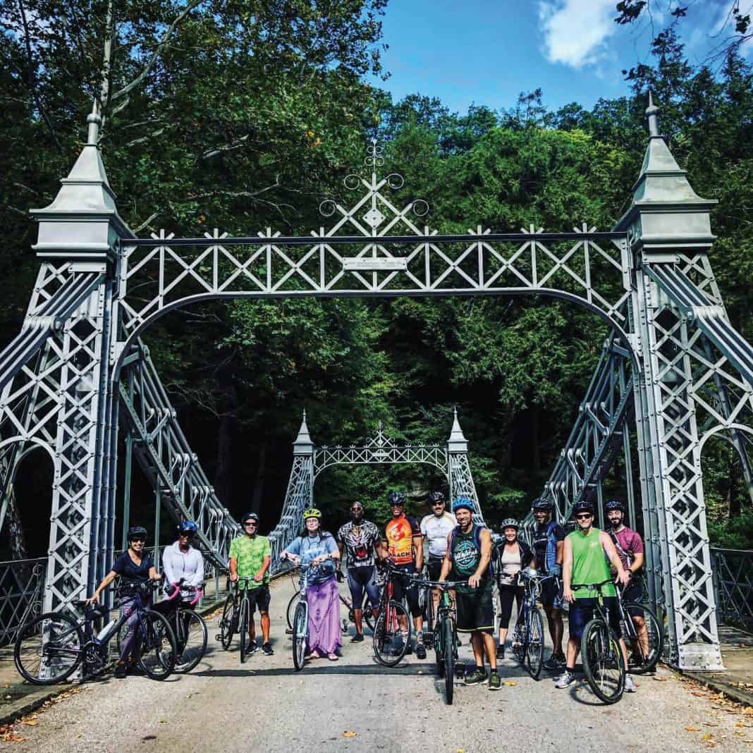 Youngstown Events | June 24-30, 2025 | Metro Monthly | Our guide covers the Youngstown-Warren area, Columbiana County and western Pennsylvania. The CycWard Bike Club hosts bike rides throughout summer. Participation is open to the community. Visit the group’s Facebook page for information. Image depicts cyclists at the silver suspension bridge at Mill Creek MetroParks. Image courtesy of CycWard Bike Club and Joe Parent. Photo by Kim Ruble.