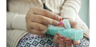 This image depicts a woman picking up a pill from a pill carrier. Penn State to offer webinars on substance-use education.